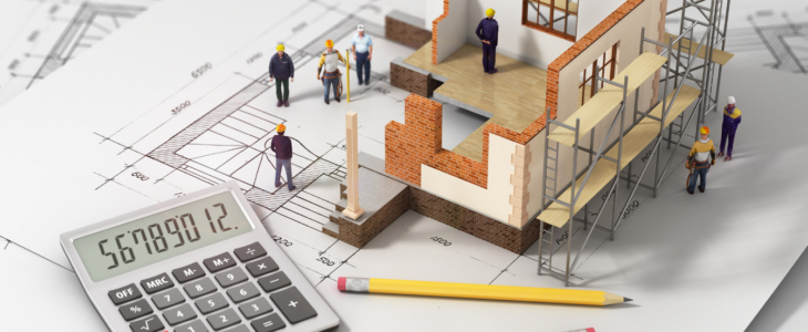 |Construction plans with miniature plastic construction workers and a calculator