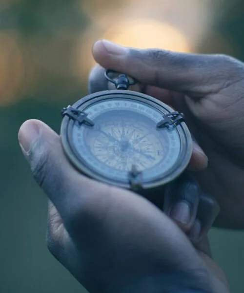 Hands holding an antique compass outdoors.