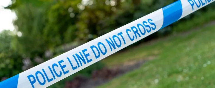 Blue and white 'POLICE LINE DO NOT CROSS' tape outdoors.