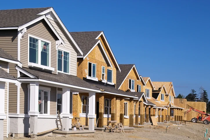 Row of partially constructed suburban houses under clear blue sky.